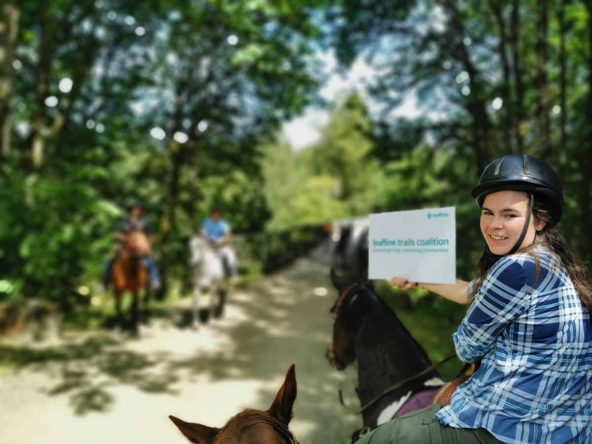 Teenage equestrian holding a Leafline sign on the Snoqualmie Valley Trail